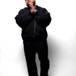 Rocky Sandoval in a black outfit against a white studio background